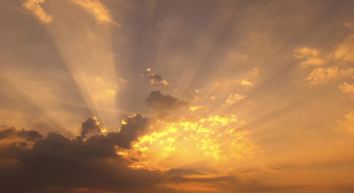 Golden sunset over clouds with sun rays shining through