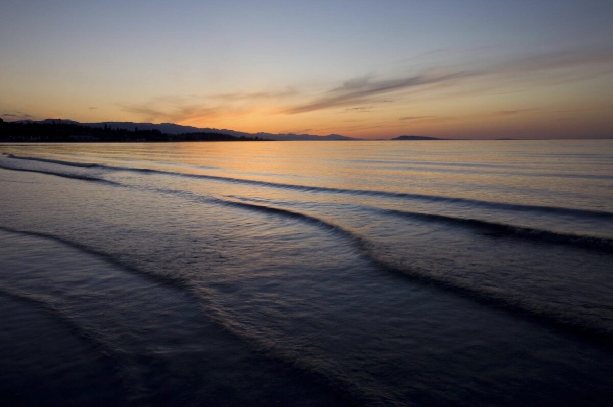 Serene sunset over calm ocean waves, peaceful beach scene